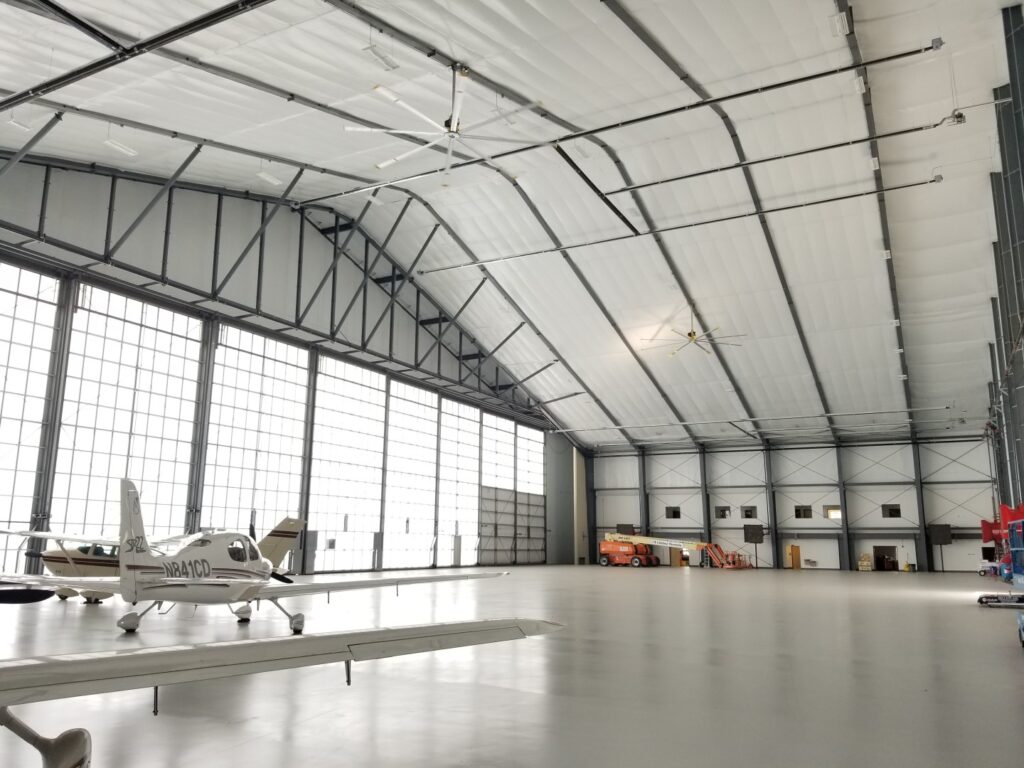 Small airplane in a spacious hoop building hangar.